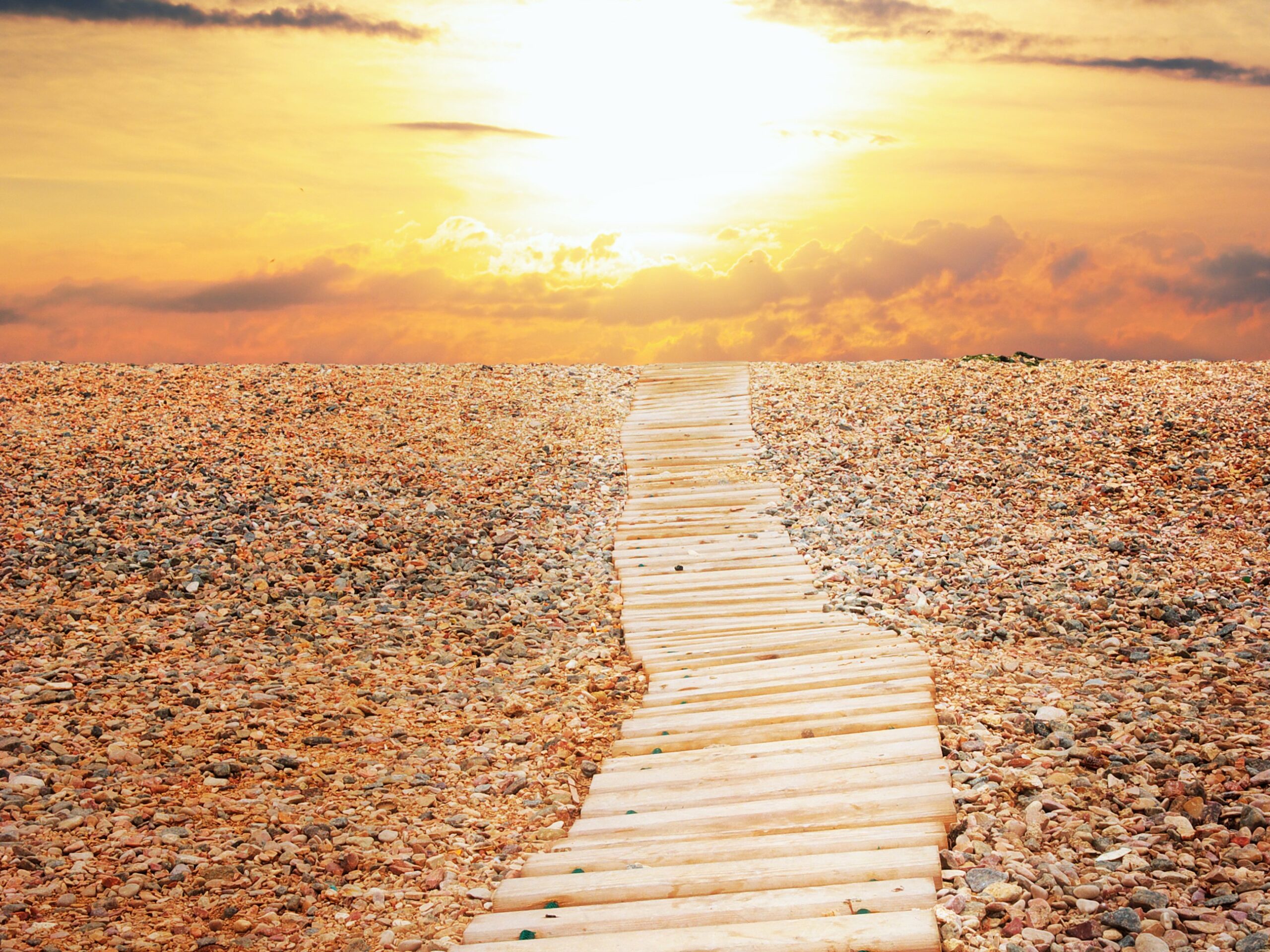 Wooden path on a rocky beach at sunset
